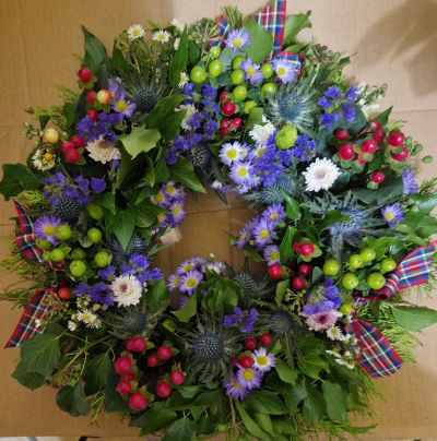 Highland Tribute - A full funeral wreath in purple, green and white tones with colourful tartan detailing.