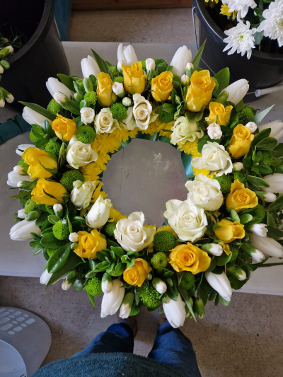 Sunshine Memories - A bright funeral wreath in cheerful yellow, white and fresh green tones, offering a warm and uplifting tribute.